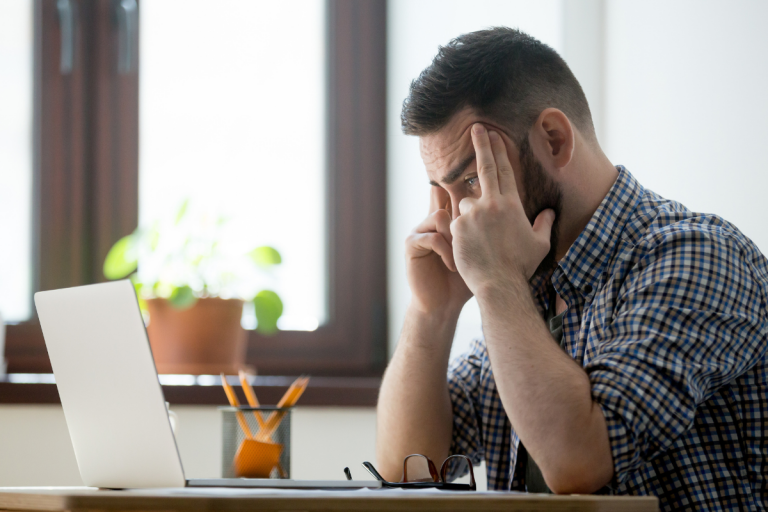 Hombre estresado frente a una computadora durante una evaluación en línea